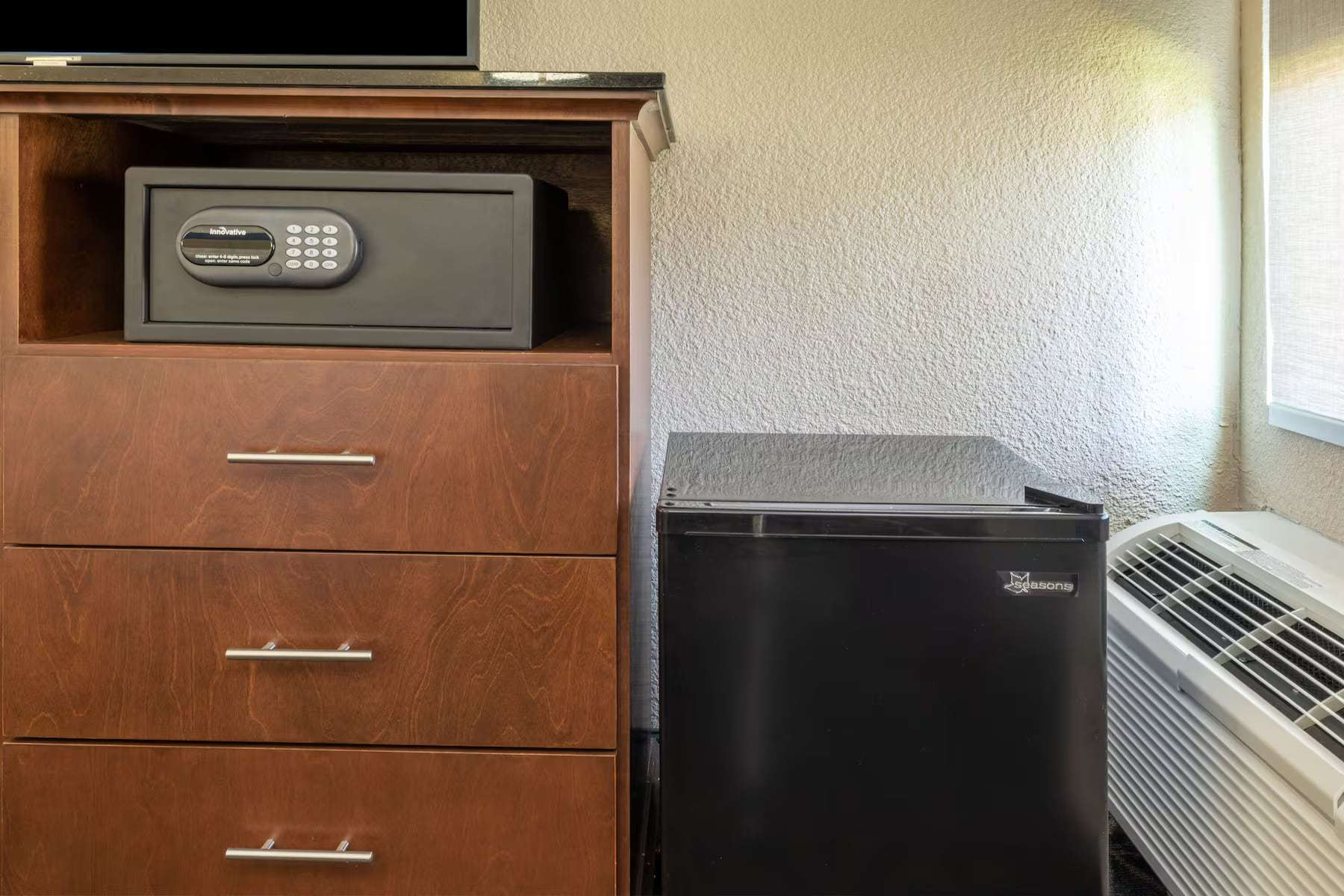 Dresser with in-room safe next to a mini fridge