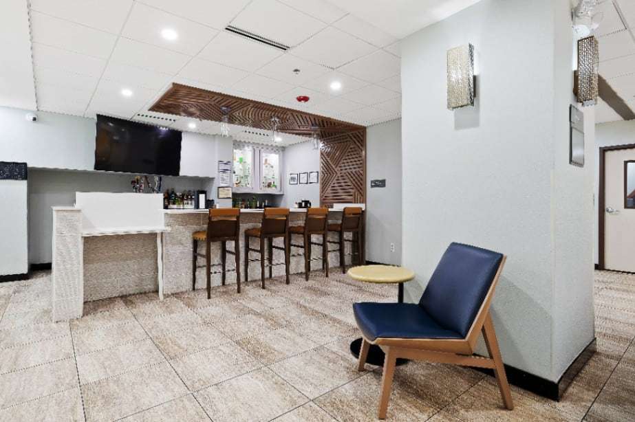 Lobby bar with stools, wood slat ceiling feature and a navy accent chair