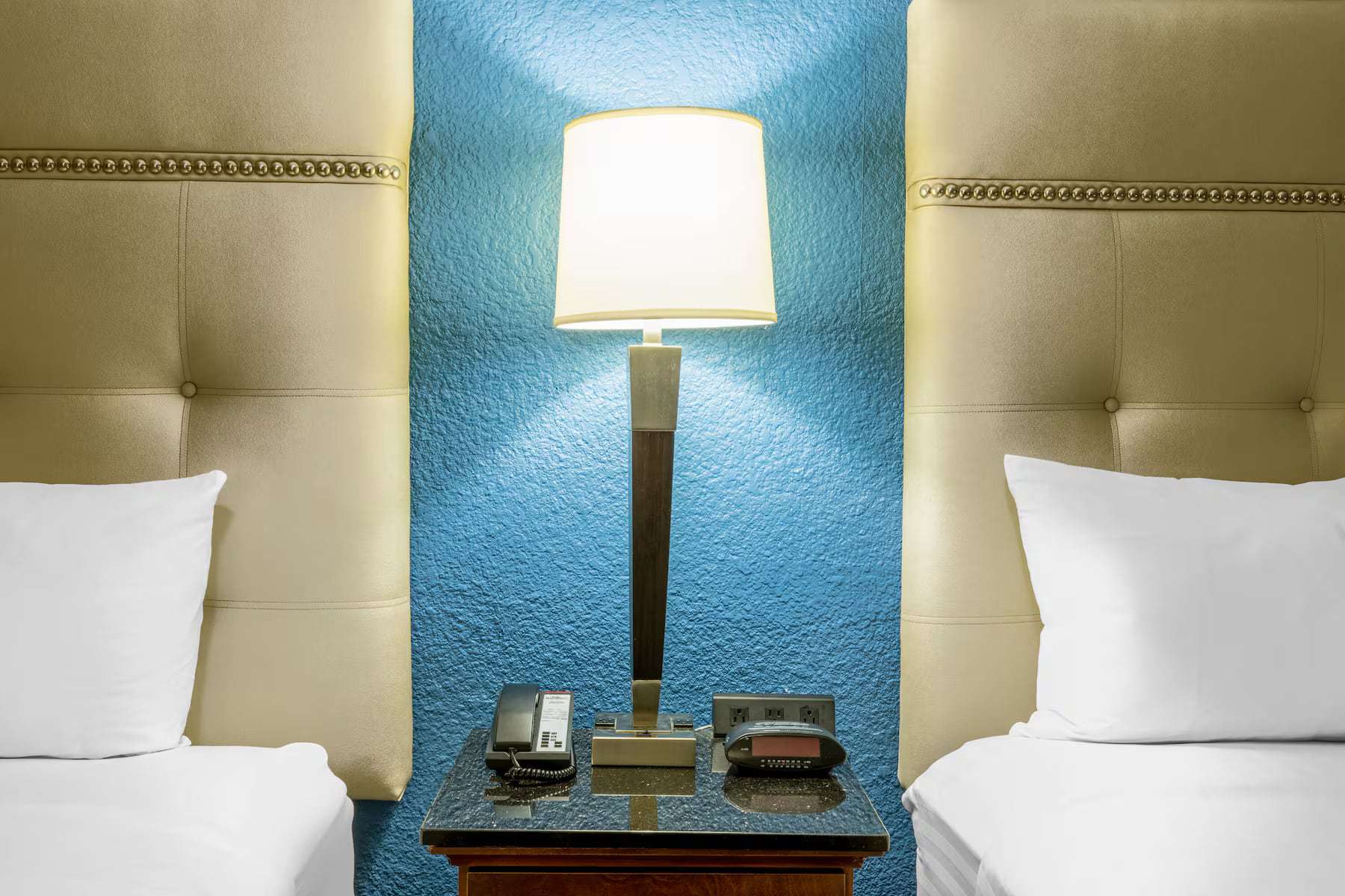 Nightstand with lamp and phones between two beds