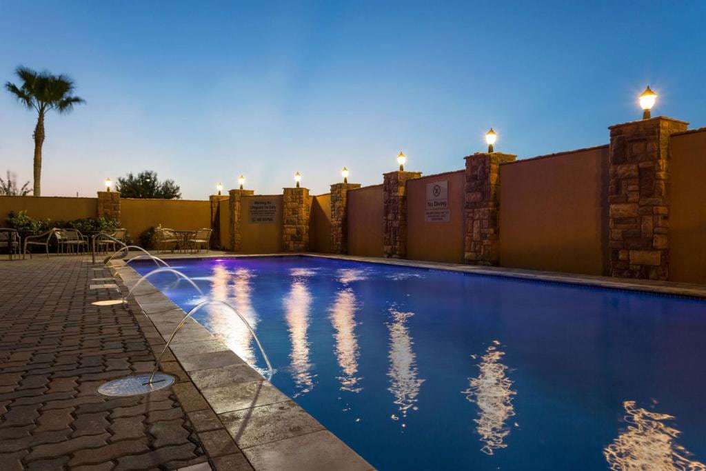 Outdoor pool at dusk with water jets, lantern-topped stone pillars and patio seating