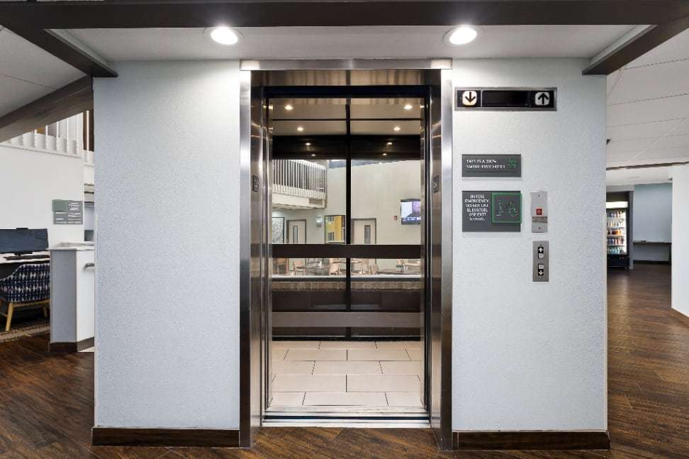 Elevator with stainless steel doors off the lobby, with wayfinding signs