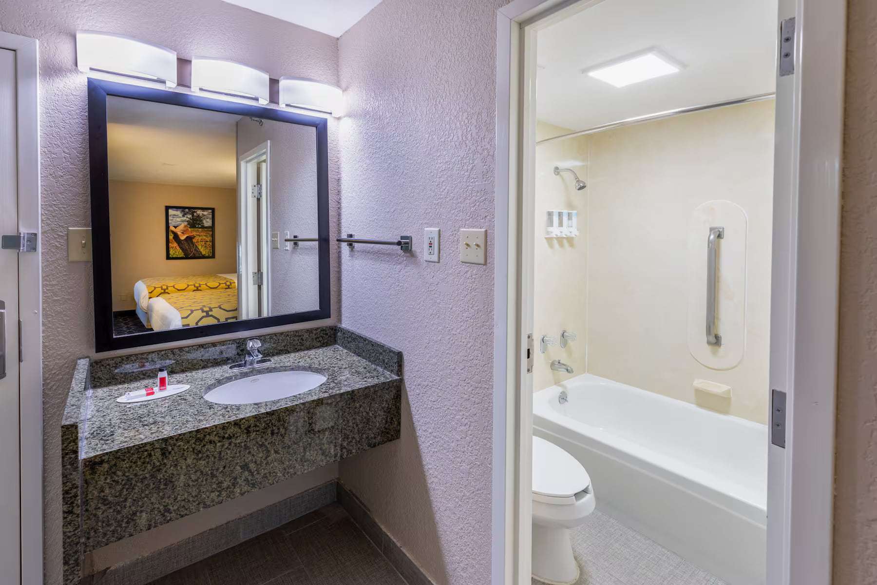 Granite vanity outside a bathroom with tub-shower and toilet