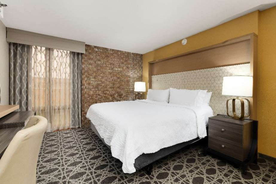 King room with upholstered headboard, brick accent wall and desk by the window