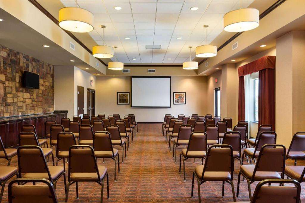 Meeting room set theater-style with projection screen, pendant lights and stone accent wall