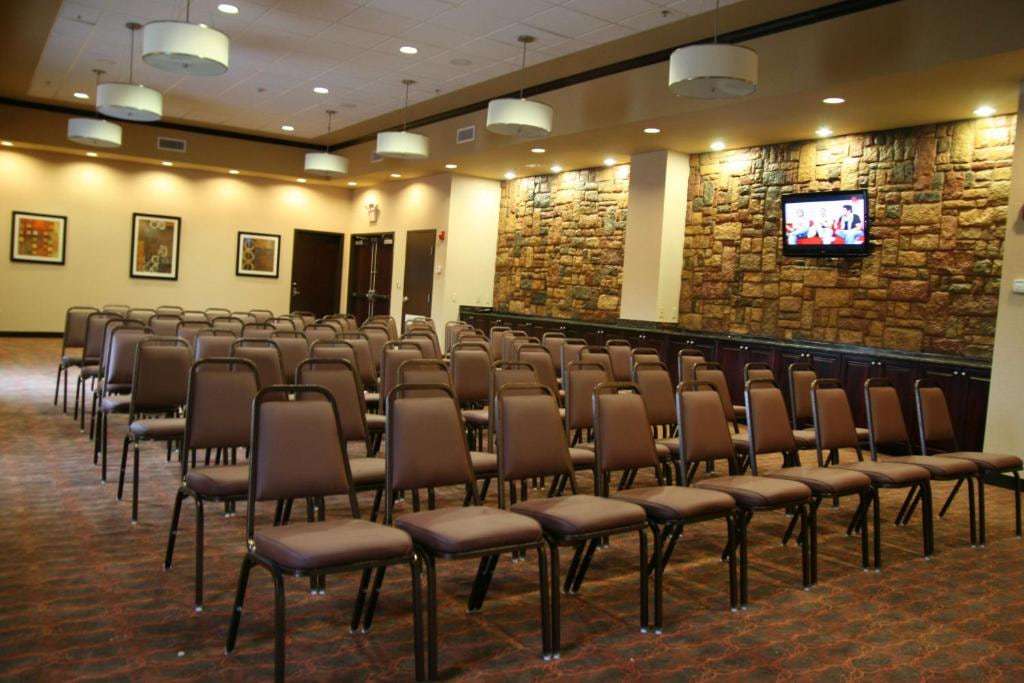 Meeting room with rows of chairs, stone accent wall, wall TV and serving counter