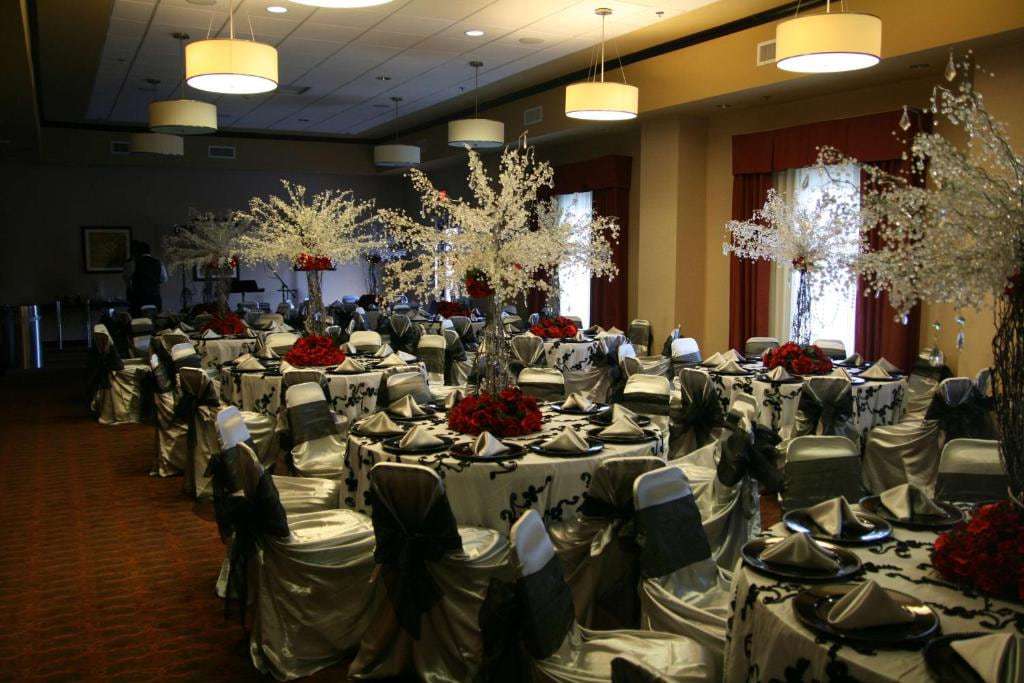 Banquet room set for a reception with draped chairs, round tables and tall floral centerpieces