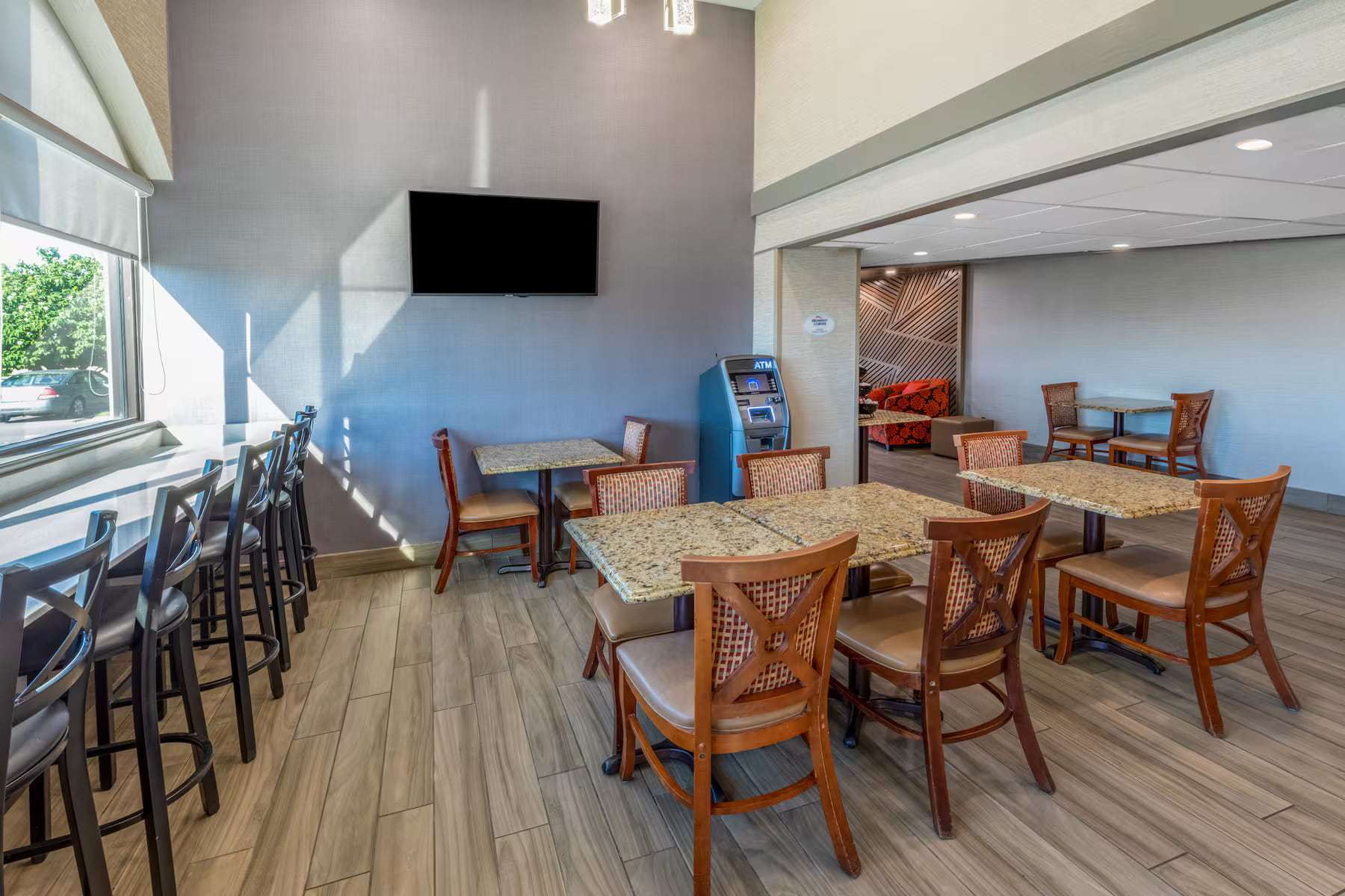 Breakfast seating with granite-top tables, window bar seating and wall TV