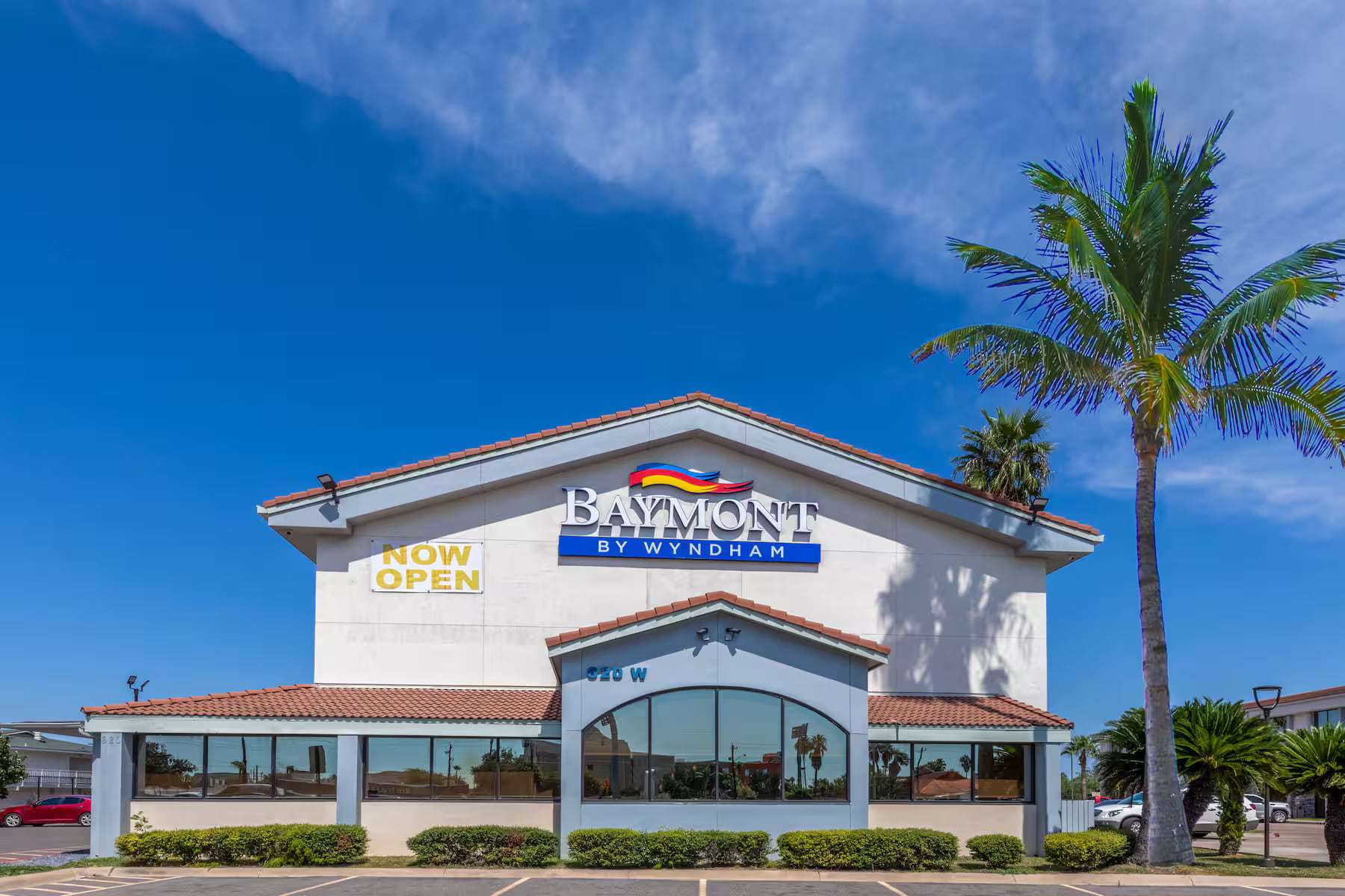 Front facade with Baymont by Wyndham sign, arched lobby window and a tall palm tree