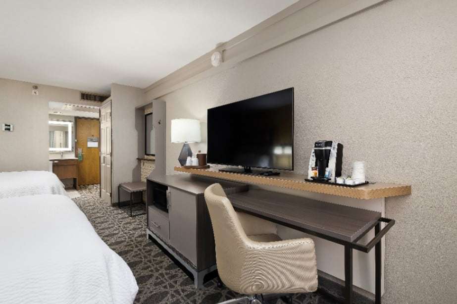 Two-bed room with TV console, microwave, coffee maker and desk, vanity by the entry