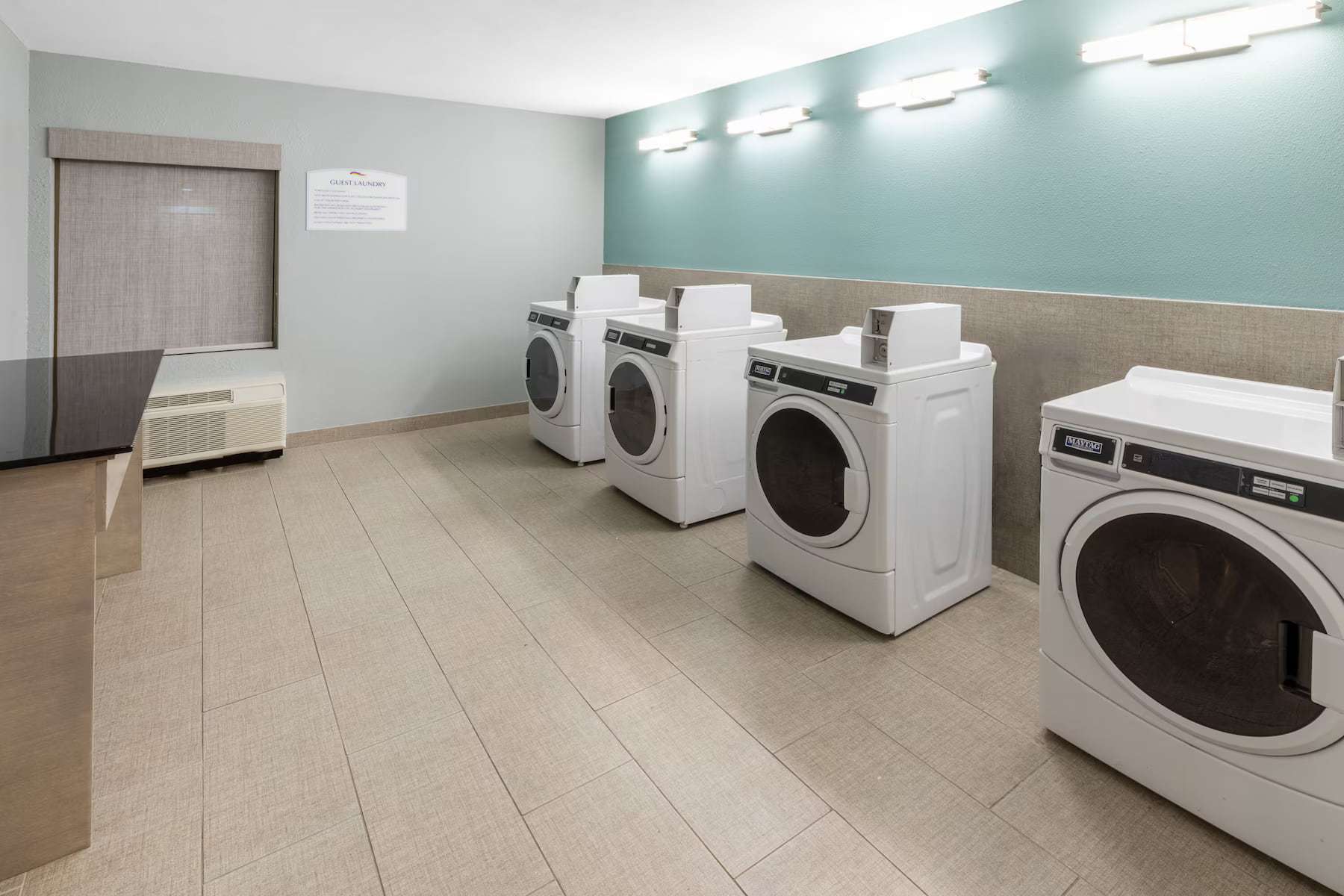 Guest laundry room with a row of front-load washers and dryers