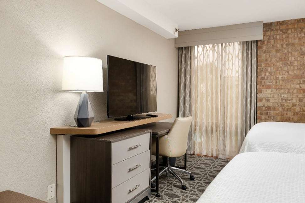 Flat-screen TV on a wood-top dresser with desk chair beside two beds