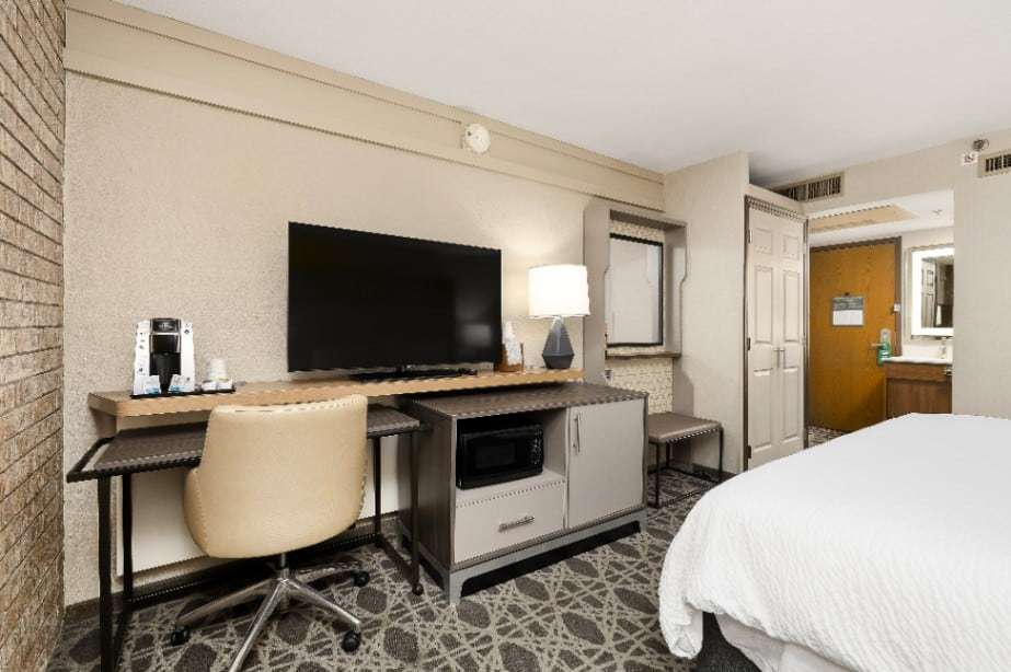 Desk, flat-screen TV and console with microwave and coffee maker near the room entry