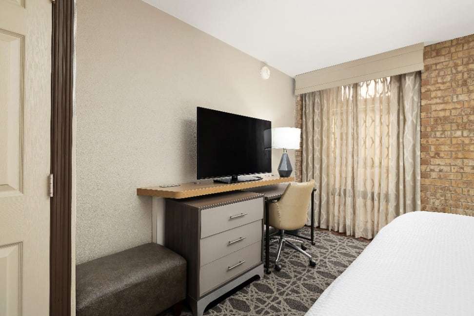 Upholstered bench, TV dresser and desk chair beside the bed near the window
