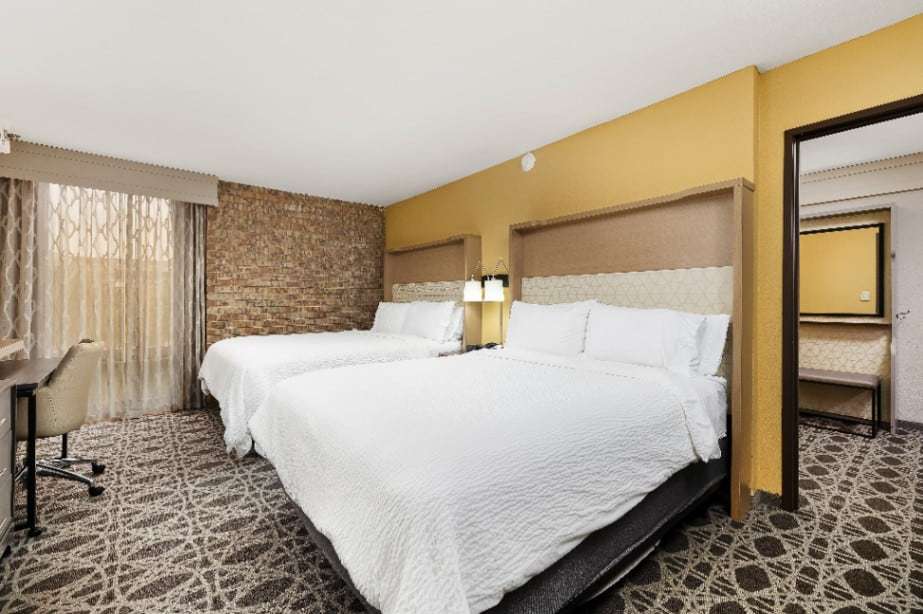Suite bedroom with two queen beds and an open doorway to the living area