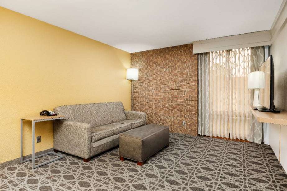 Suite living area with sleeper sofa, ottoman, side table and brick accent wall