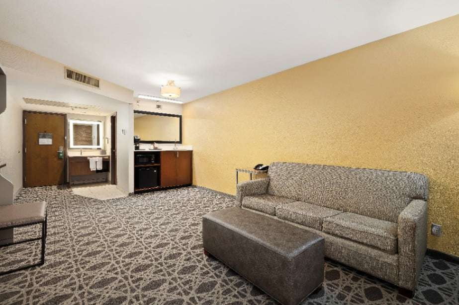 Suite living room with sofa and ottoman, with the wet bar and entry in the back