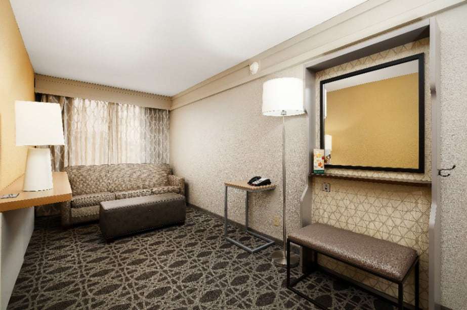 Suite sitting area with sofa, ottoman, floor lamp and mirror with bench