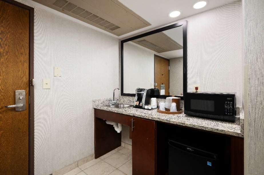 Roll-under granite counter with sink, coffee maker, microwave and mini fridge by the door