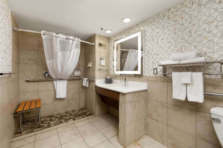 Accessible roll-in shower with fold-down bench, grab bars and roll-under sink