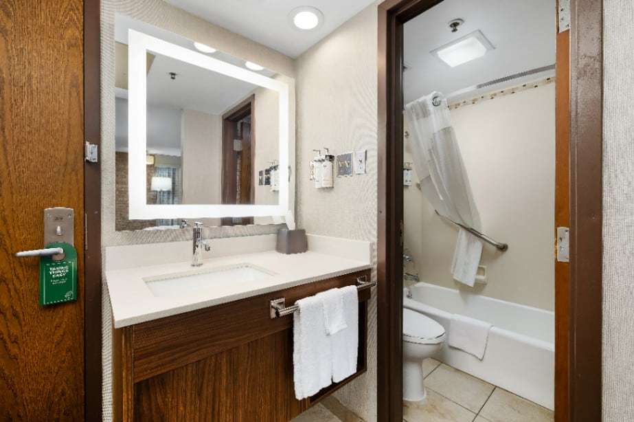 Lighted vanity mirror and sink, with tub-shower and toilet in the next room