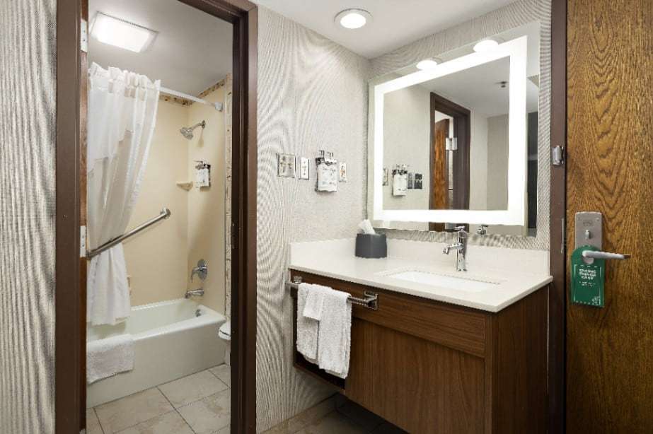Bathroom with tub-shower and grab bar, and a separate vanity with lighted mirror