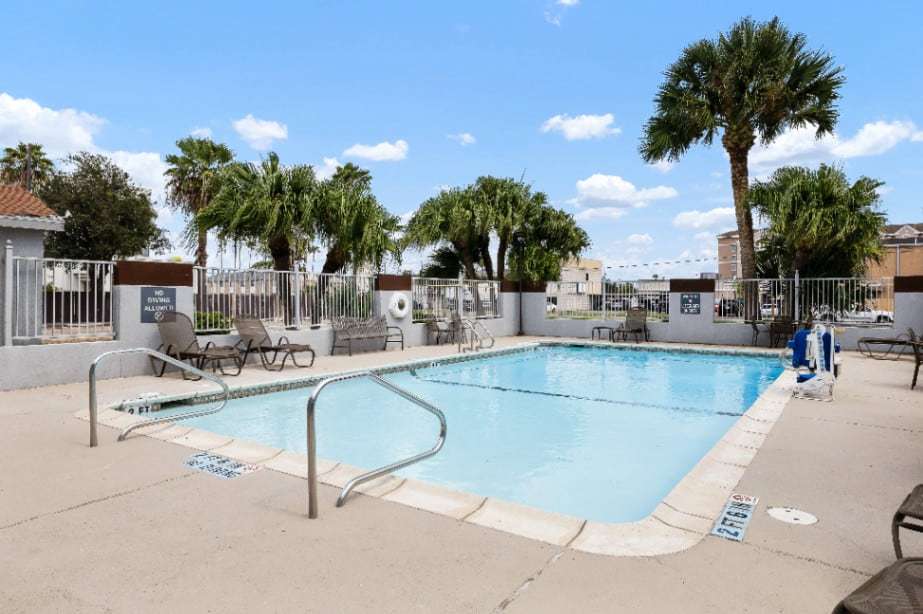 Outdoor pool with pool lift, lounge chairs and palm trees under a blue sky
