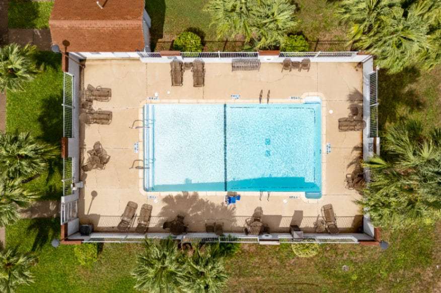 Overhead drone view of the rectangular outdoor pool with lounge chairs and palms