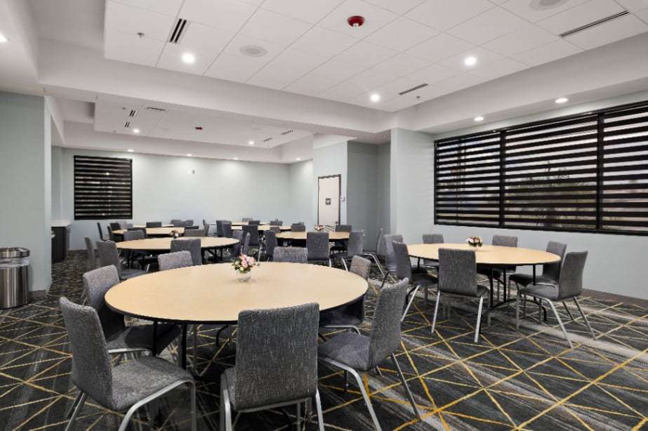 Event room with round tables, gray chairs and patterned carpet