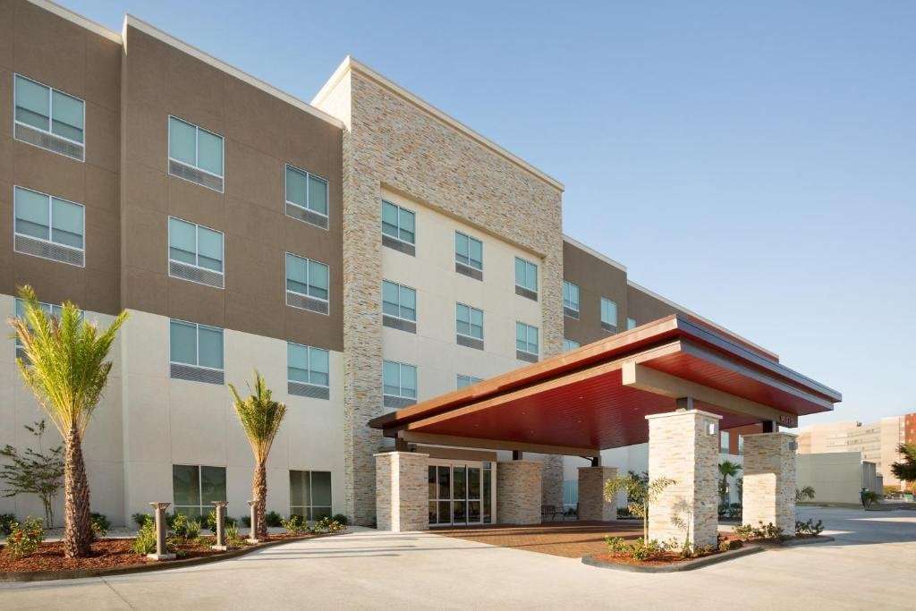 Four-story hotel exterior with stacked-stone tower, red porte-cochere entrance and palm-lined drive