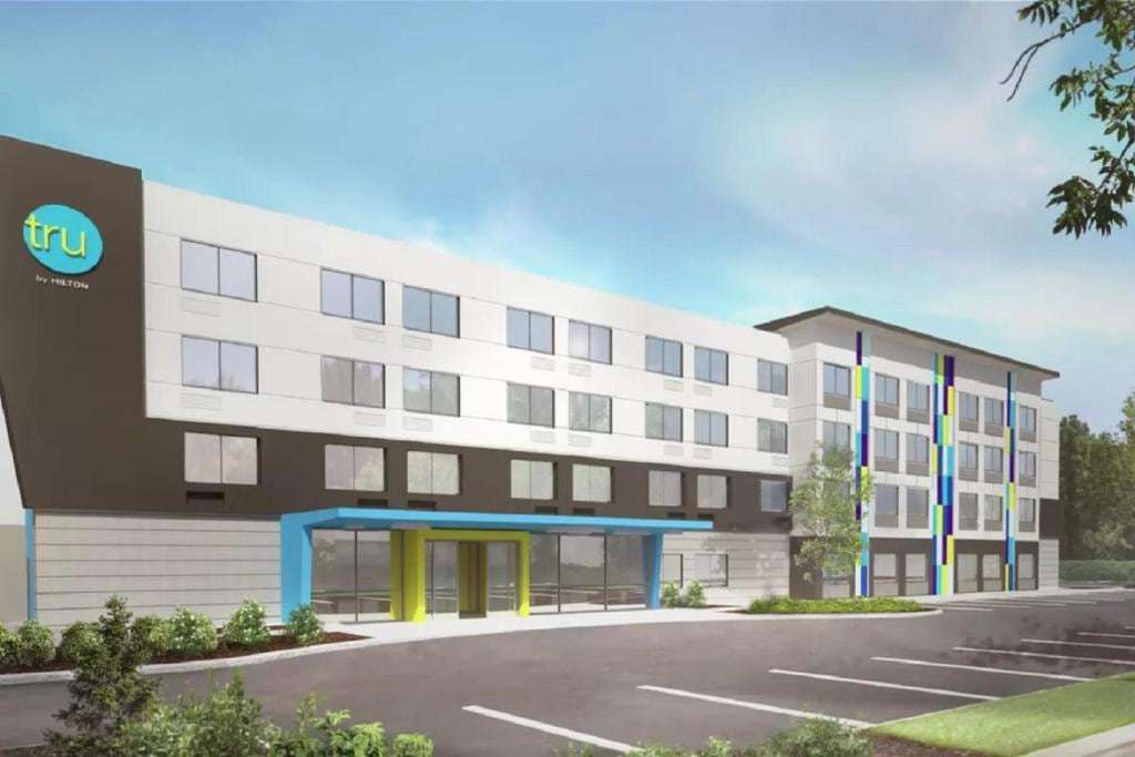 Rendering of a four-story Tru by Hilton hotel with a blue and lime entrance canopy and parking lot