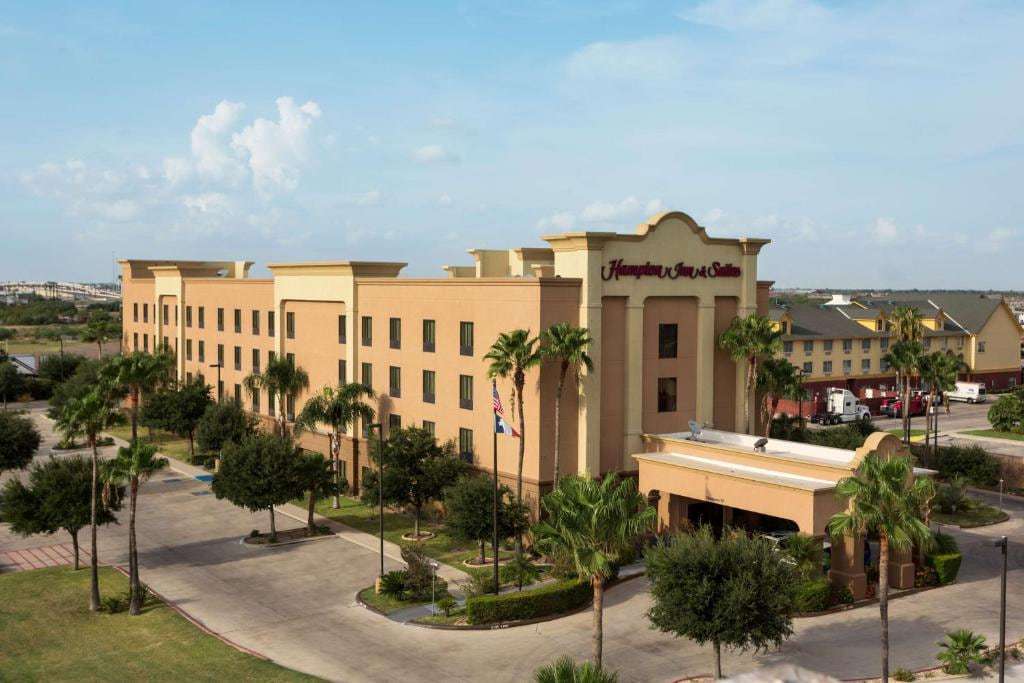 Aerial view of the hotel with palm-lined drive, porte-cochere and flags under a blue sky
